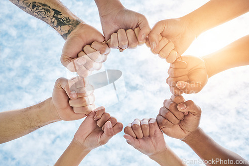 Image of Hands in circle, fist and blue sky, community in collaboration for support and diversity together from below. Teamwork, power hand sign and sunshine, positive group of people in solidarity and huddle