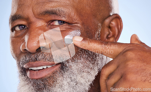 Image of Skincare, cream and portrait of black man in studio for sunscreen, anti aging or beauty. Cosmetics, closeup or self care with lotion on face of model on blue background for facial, spa and product