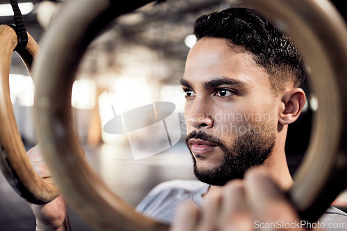 Image of Athlete man, gymnastic rings and gym for a training workout with focus and commitment. Face of serious male person with pull up exercise for strong muscle, power and fitness training with balance