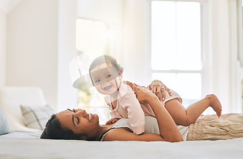 Image of Mom lying, lift newborn and bed with smile, care and happiness in morning with love, bond or excited face. Young mother, baby and happy in bedroom, family home and holding kid with pride in sunshine