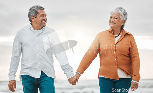 Image of Senior happy couple, walk beach and holding hands for smile, bond and care with romance, love and vacation. Elderly man, woman and sunset with happiness, retirement and travel by ocean for holiday