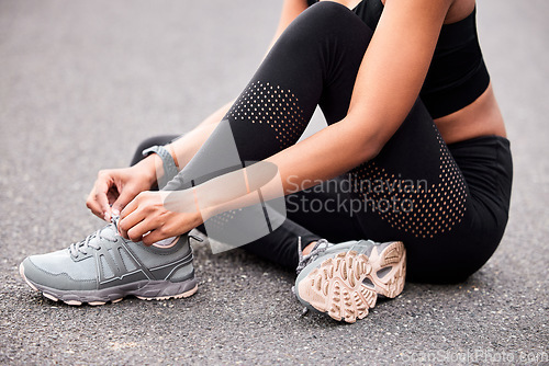 Image of Fitness, woman tying shoes and sitting road for safety during outdoor marathon training. Running, cardio health and wellness, female athlete fixing laces on footwear and feet of runner on asphalt.