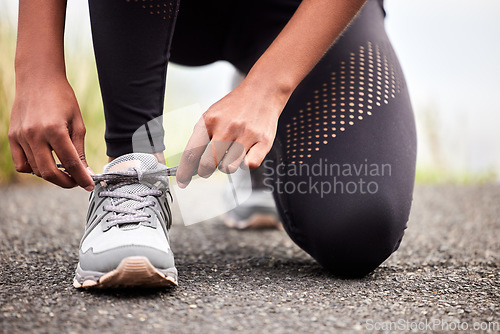 Image of Fitness, feet of woman tying shoes and runner on road for safety during outdoor marathon training. Running, cardio health and wellness, female athlete fixing laces on footwear and closeup of asphalt.