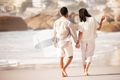 Image of Couple walking on beach, holding hands and back view with ocean, travel and vacation with love and bonding outdoor. Mockup space, summer and people together in nature with relationship and commitment