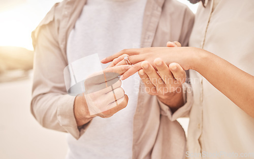 Image of Couple, hands and engagement in closeup at beach with care, achievement or love on vacation in sunset. Man, woman and ring with marriage offer by ocean for proposal, future and together on holiday