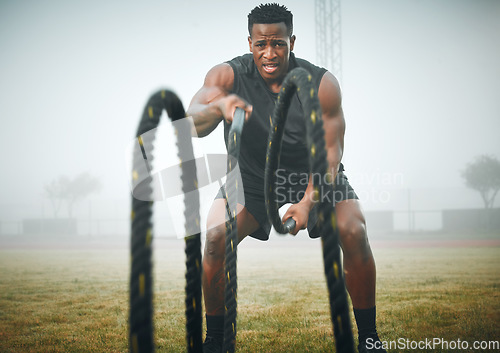 Image of Fitness, battle rope and black man on field for power workout, body building and training muscle strength. Exercise, sports and African bodybuilder on grass with ropes, energy and outdoor performance