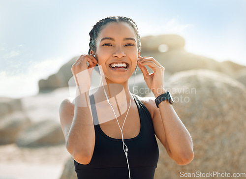 Image of Happy woman with earphones, fitness at the beach and listening to music for motivation and workout outdoor. Exercise, health and smile, female athlete streaming online with radio and audio in nature