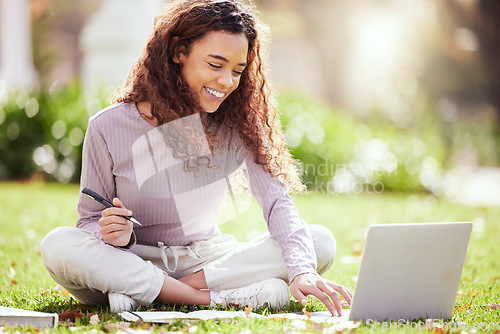 Image of Woman sitting on lawn, laptop and college student on campus, studying with course material and education. Happy female person outdoor, learning and study online notes on pc with academic scholarship