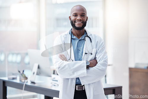 Image of Doctor, portrait of a black man with his arms crossed and in his office at his workplace with a lens flare. Confident or proud, happy and male scientist or surgeon with arm folded in a laboratory