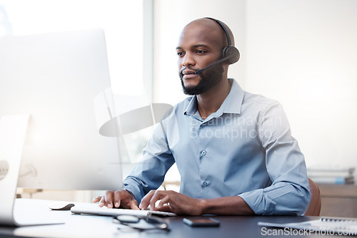 Image of Black man typing at computer, call center and contact us, communication and concentrate with headset. Male agent with focus, customer service and help desk employee with online support and email