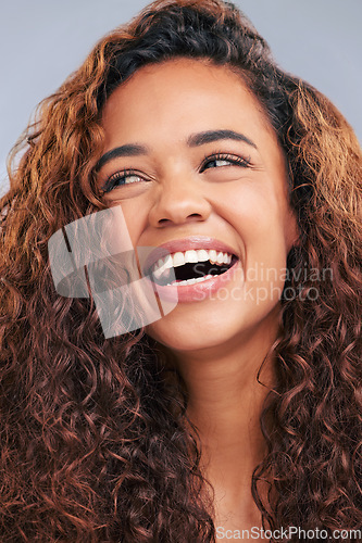 Image of Laughing, curly hair and natural woman in studio with smile and face glow. Happy female person with beauty and healthy curls as benefits or results of shampoo or cosmetics on a grey background