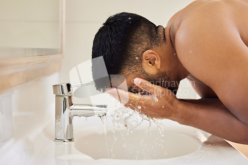 Image of Man washing face, water splash and beauty in bathroom, skincare and cleaning skin with water for morning routine. Male person at home, grooming and natural cosmetic care, clean facial and hygiene