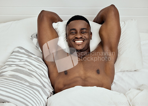 Image of Portrait, topless man and smile in bed, room and home for comfortable break, relax and good morning. Strong and happy black male wake up in bedroom from sleep, rest and stretching muscular body