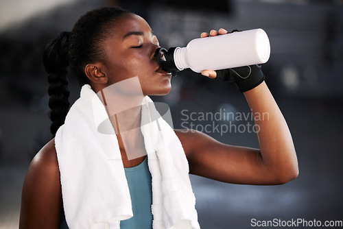 Image of Relax, fitness or black woman drinking water in gym after training, workout or exercise to hydrate her body. Fatigue, wellness or tired girl with bottle for healthy liquid hydration on resting break