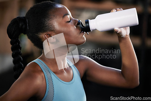 Image of Tired, fitness or black woman drinking water in gym after training, workout or exercise to relax or hydrate body. Fatigue, fitness or girl with bottle for healthy liquid hydration on resting break