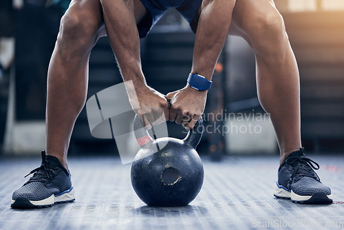 Image of Exercise, floor and kettlebell with a bodybuilder man in the gym for a weightlifting workout routine. Fitness, hands and strong with a male athlete holding a weight in a sports club while training