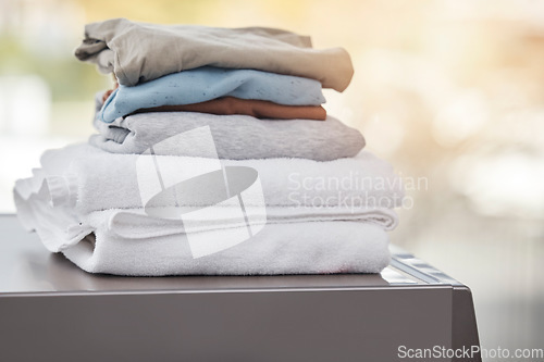 Image of Home, clothes on a washing machine and laundry day with a lens flare. Cleaning or hygiene, appliances or mockup space and folded clean pile of clothing on a wash dryer at a house for housework