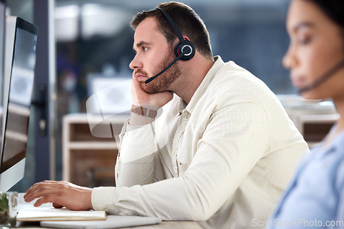 Image of Mental health, man with headset and computer at his desk in a modern office at workplace. Telemarketing or online communication, customer service and male call center agent bored at his workstation