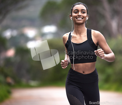 Image of Running in nature, woman with earphones and fitness, mockup space and smile on healthy workout on path. Exercise, health and wellness, happy girl runner on forest path with music and training mindset