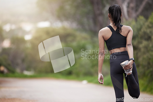 Image of Nature, woman and warm up from back, workout motivation and fitness while stretching legs. Dedication, commitment and girl runner standing on road with leg stretch for outdoor run and exercise goals.