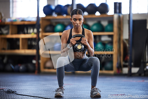 Image of Portrait of woman in gym, kettlebell and squat for weightlifting, power and muscle with focus at sports club. Balance, fitness and fit female bodybuilder lifting weights and training with health goal