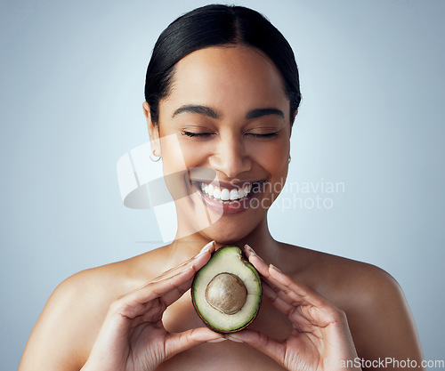 Image of Smile, hands and woman with avocado in studio for skincare, organic or facial on grey background. Face, avo and girl model with fruit for eco, vegan or detox with omega 3, collagen and vitamin c