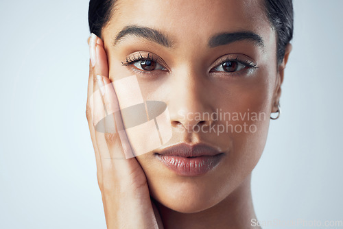 Image of Skincare, beauty and hands on face of Indian woman in studio for natural, cosmetics and dermatology on grey background. Portrait, soft and female model feeling skin, results and glowing wellness