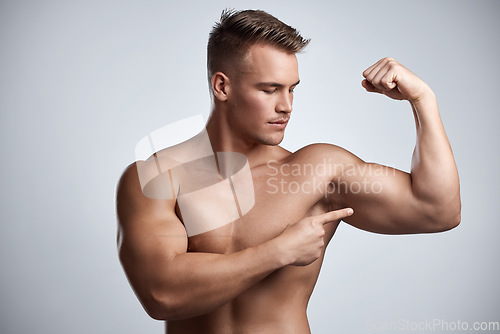 Image of Man, bodybuilder and pointing to bicep in studio, background and exercise for muscular power. Strong, sexy and topless male model, sports athlete and flex arm muscle with pride of fitness results