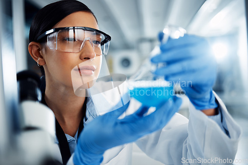 Image of Woman, scientist and study chemical liquid, glass beaker and science chemistry experiment in lab. Female doctor with goggles, gloves and analysis of fluid, scientific innovation and medical research