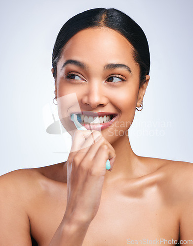 Image of Woman, brushing teeth and studio with thinking, smile or self care for dental wellness, health or white background. Girl, dentistry model and toothbrush with toothpaste, product or happy for cleaning