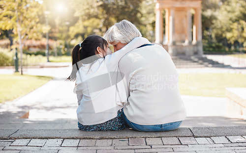 Image of Girl, grandmother and hug in the outdoor for trust or secret in family with grass and sunshine. Kid, hugging and grandma with back of together at the park with a whisper in summer to relax in nature.