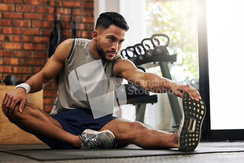 Image of Gym, man and stretching legs for warm up, training motivation and fitness mindset for workout with hand on foot. Focus, commitment and male athlete on floor to stretch at sports club for exercise