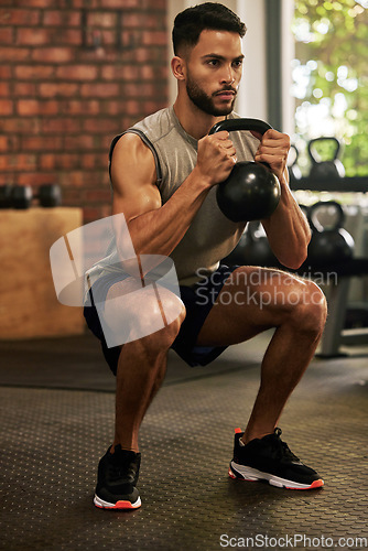 Image of Squat, fitness and man with kettle bell in gym for exercise, bodybuilder training and workout. Sports, strong muscle and serious male person lifting weight for wellness, healthy body and strength