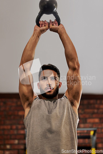 Image of Muscle, fitness and man focus with kettlebell in gym for exercise, bodybuilder training and workout. Sports, strength and serious male person lift weight for wellness, healthy body and power