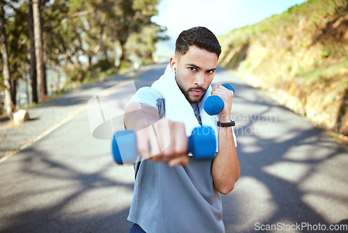 Image of Man, dumbbell and punch in nature fitness for exercise, workout or training in the outdoors. Portrait of fit, active and sporty male person punching with weights in healthy outdoor cardio endurance