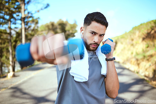 Image of Man, dumbbell and punches in nature fitness for exercise, workout or training in the outdoors. Portrait of fit, active and sporty male person punching with weights in healthy outdoor cardio endurance