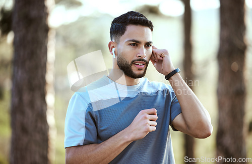 Image of Fitness, man and outdoor with earphones for music on run or workout for motivation. Male athlete person or runner listening to audio in nature forest for training exercise, running and wellness goals