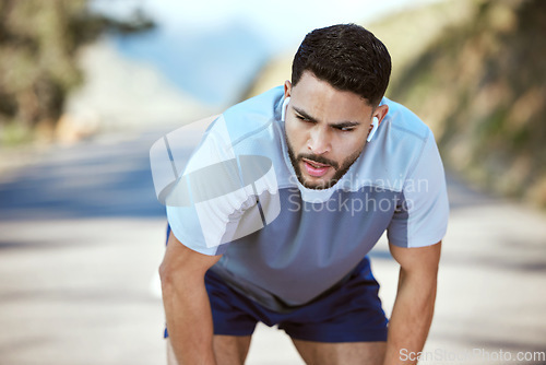 Image of Fitness, tired man and outdoor with earphones for music on run or workout. Exhausted athlete person or runner listening to audio on break and road for exercise, running and training or breathing