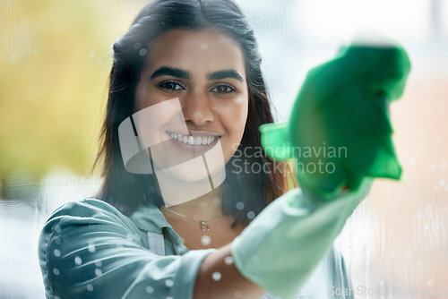 Image of Housekeeping, portrait and cleaner cleaning the window with a cloth by her home or apartment. Female maid, housekeeper or wife washing the glass door with detergent product for bacteria, dirt or dust