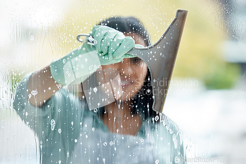 Image of Housekeeping, foam and woman cleaning the window with equipment by her home or apartment. Female maid, cleaner or housewife washing the glass door with detergent product for bacteria, dirt or dust.