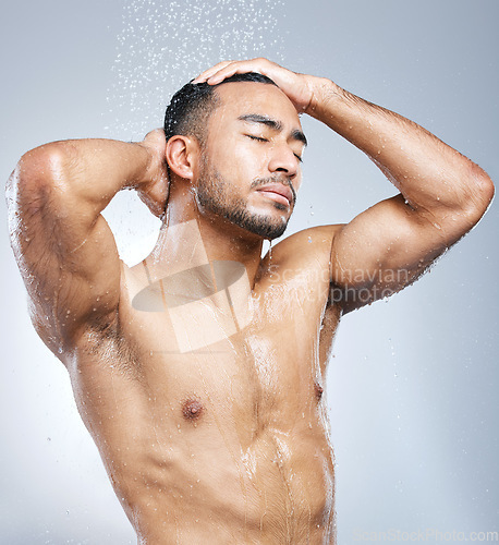 Image of Man in shower with blue background, cleaning and skincare for hygiene with shampoo, healthy body and studio backdrop. Water, skin and hair care, male model washing in bathroom spa with self love.