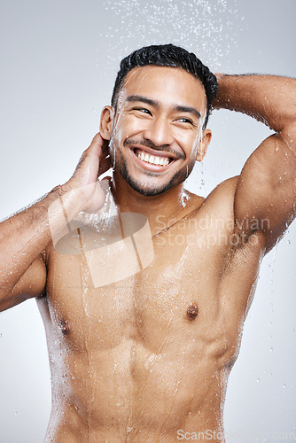 Image of Man in shower with smile, cleaning and studio background for hygiene with shampoo, healthy body. Water, skin and hair care, happy male model washing with happiness on backdrop with bathroom spa time.