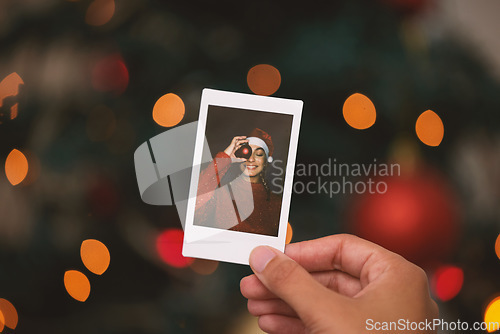 Image of Hand, christmas and picture with a person looking at a photograph of a memory on a blurred background. Home, nostalgia and holidays with an adult holding a photo to remember past memories on xmas eve