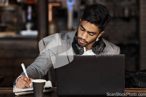 Image of Young business man, writing and cafe with notebook, laptop or plan for schedule, report and analysis. Indian businessman, book and pen for ideas, brainstorming or web design with focus in coffee shop