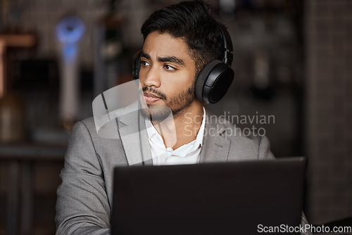 Image of Business man, thinking and cafe for remote work with headphones on laptop, planning and report. Young indian businessman, solution and brainstorming for ideas, web design and music in coffee shop