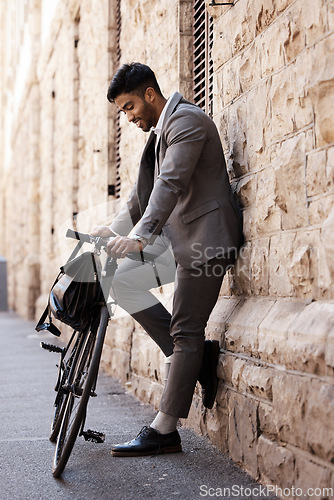 Image of Bicycle, relax and happy business man in city for carbon neutral, sustainable and transport. Bike, commute and Indian male person on cycling break, smile and resting while traveling alone in Europe