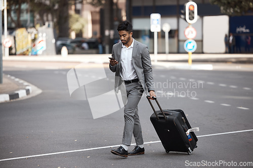 Image of Phone, travel and luggage with a business man walking in the city for an international trip. Mobile, communication and suitcase with a young male employee typing a text message on a street commute