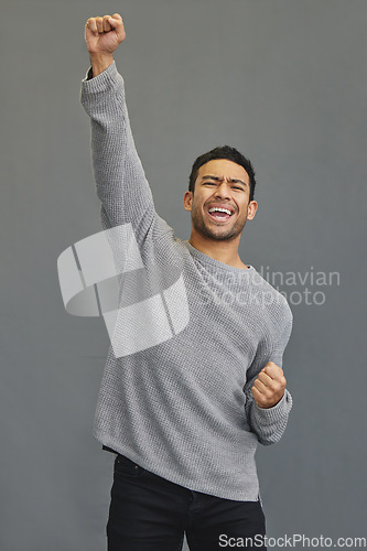 Image of Celebrate, winner and man in a studio cheering for success, winning or champion achievement. Happiness, excited and male model with fist pump in celebration of a victory isolated by a gray background