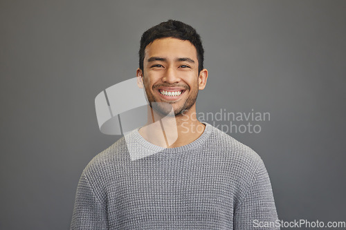 Image of Portrait of man in studio with smile, happy mindset on studio backdrop in Indonesia and casual fashion. Relax, confidence and natural face of calm Asian male model on grey background with happiness.