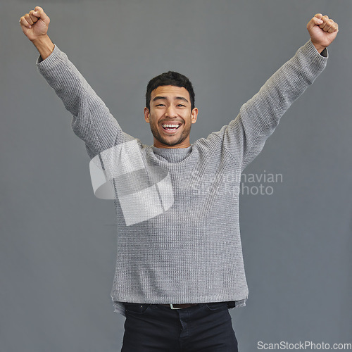 Image of Celebration, happy and portrait of a man in a studio cheering for success, winning or achievement. Happiness, excited and male model winner with fist pump to celebrate a victory by a gray background.